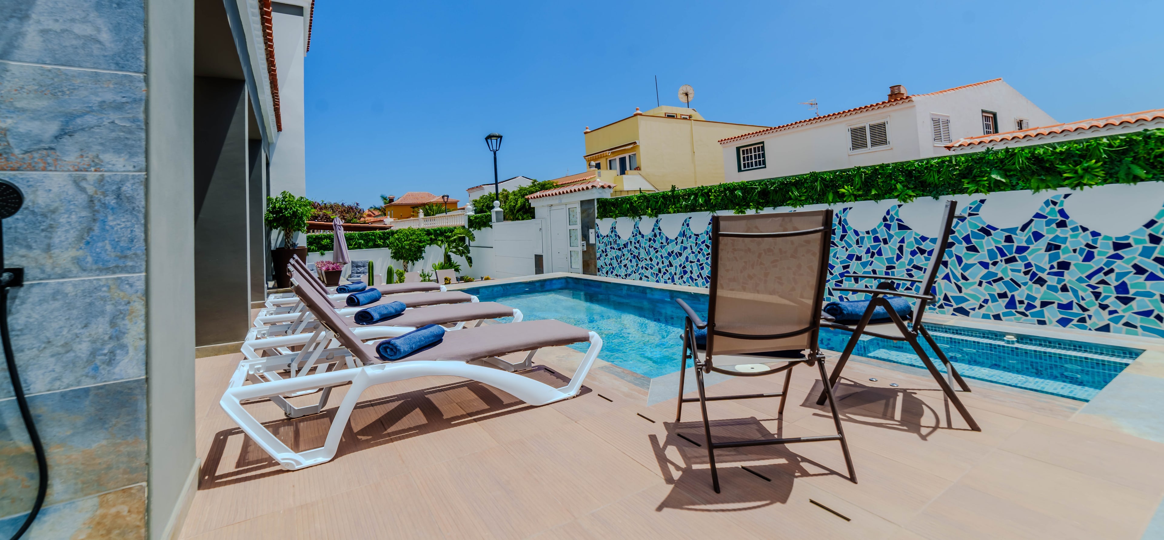 Piscina privada con jacuzzi elevado adjunto, rodeada por un muro de mosaico azul con forma de olas