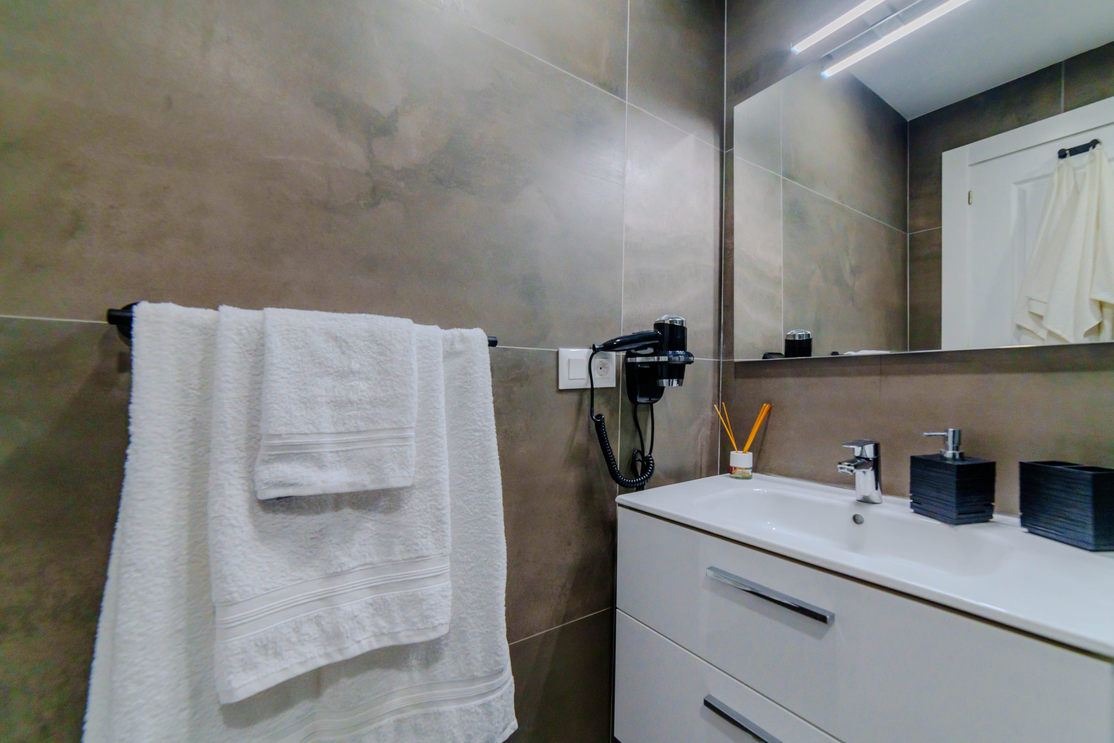Baño en suite moderno con mueble de lavabo amplio, espejo y toallas limpias